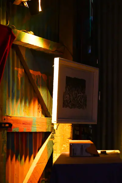 Detalle de chapa, madera, obra enmarcada y luz cálida dentro del galpón