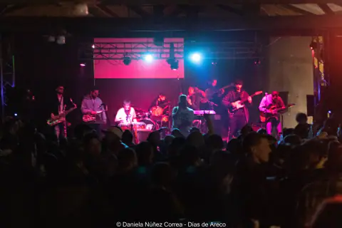 Concierto con banda en escenario y multitud en primer plano