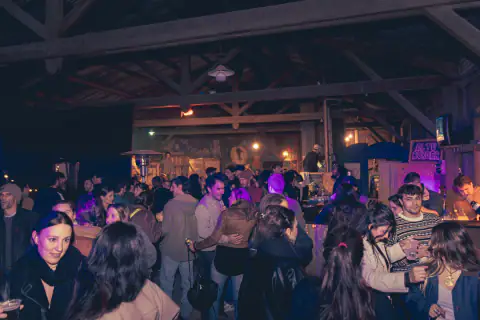 Noche de encuentro con grupos conversando dentro del galpón
