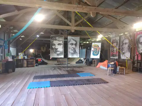 Interior amplio con piso de madera, retratos colgados y estructura de galpón